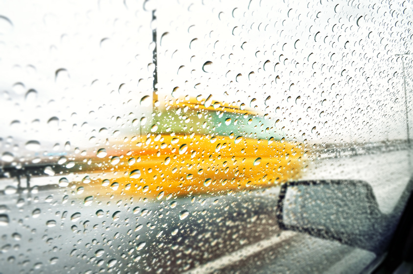 Blurry yellow car behind raindrops